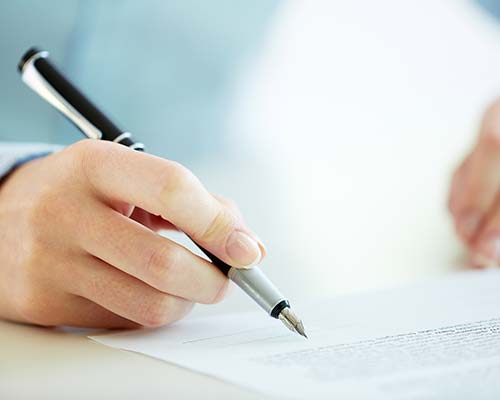 person holding a pen above a document